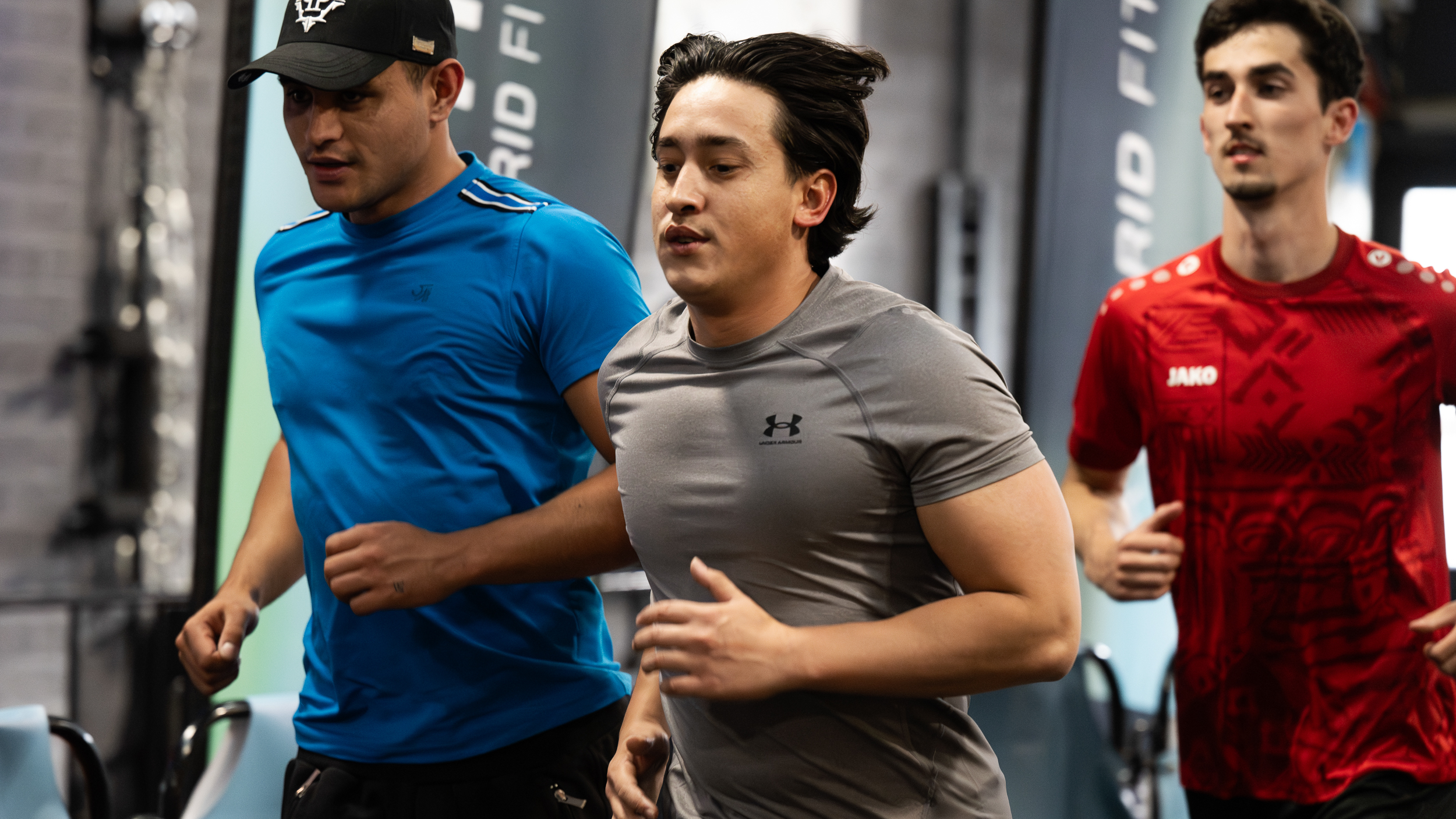 Drie atleten rennen zij aan zij tijdens de STYREKX hybrid fitness race.